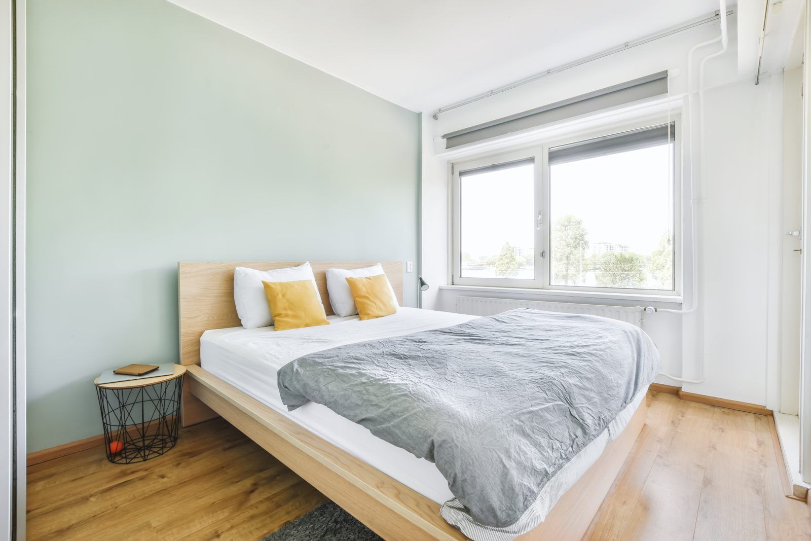 Dormitorio con cama, almohadas, mesita de noche y ventana